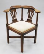 A George III elm corner chair, with wide arm rests, shaped pierced splat backs and drop-in seat