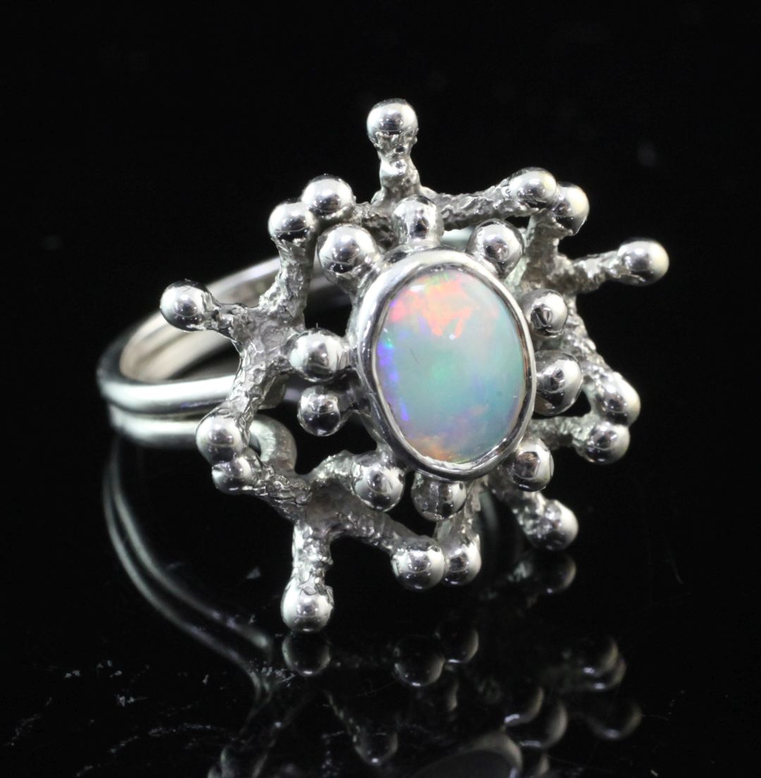 A 1970's 9ct white gold and white opal set free form ring by John Donald, with central oval stone,