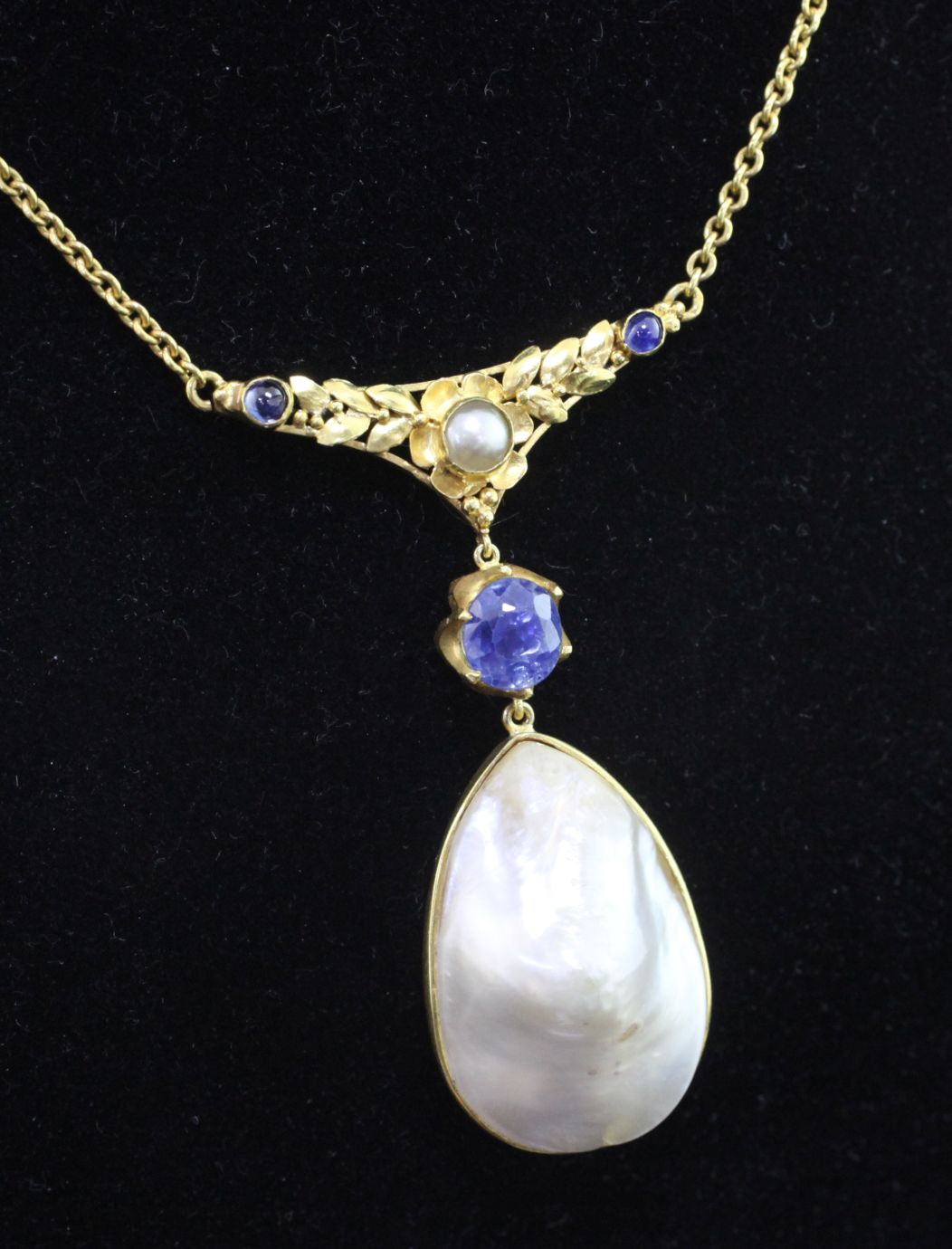 A high carat gold, baroque mabe pearl and sapphire set pendant necklace, with pierced foliate