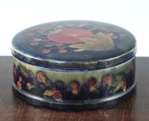 A William Moorcroft pomegranate circular box and cover, c.1920, with a green / cobalt blue mottled