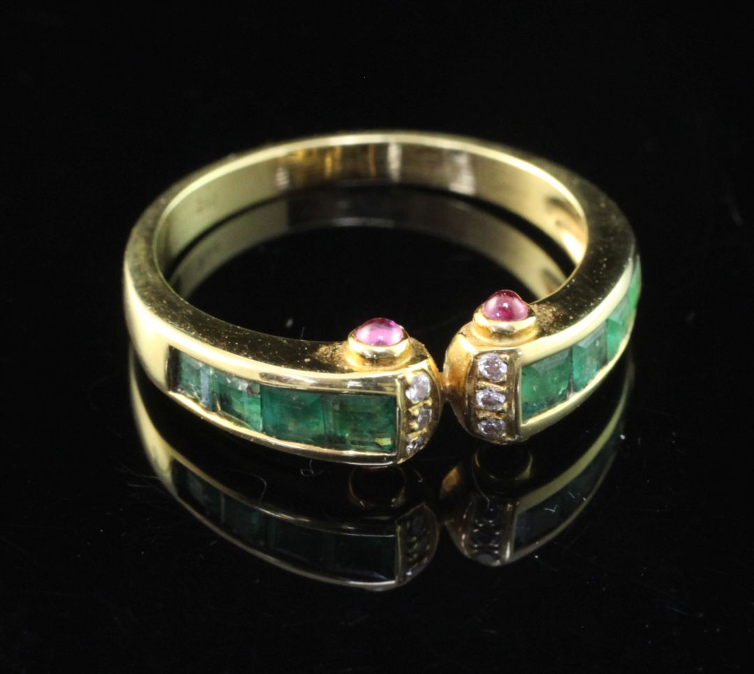 A stylish 18ct gold, emerald and diamond ring, with cabochon ruby set terminals, size O.