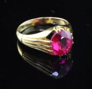 An early/mid 20th century gold and solitaire synthetic ruby claw set ring, with fluted shoulders,