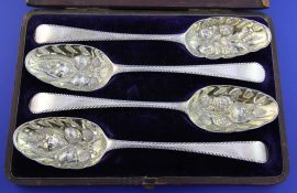 A cased set of four George II silver table spoons later decorated as berry spoons with gilded bowls,