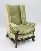 A William & Mary style carved walnut wingback chair, the scrolling foot rail with central pierced