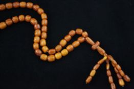 A single strand honey coloured amber bead tassel drop necklace, gross weight 79 grams, overall