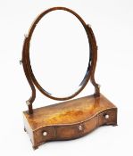 A George III mahogany and rosewood crossbanded oval toilet mirror, the serpentine base fitted with