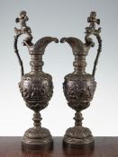 A pair of classical style bacchanalian bronze ewers, the ovoid bodies decorated with cherub scene,