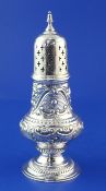 A late Victorian repousse silver sugar caster, with foliate scroll decoration and turned finial,