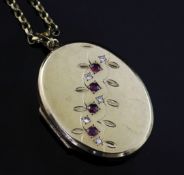An early 20th century 9ct gold, ruby and diamond set oval locket, on a 9ct gold chain, gross