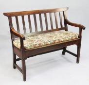 A small 18th century oak bench, with slat back and open arms, on tapering square section supports,