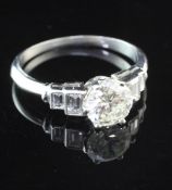 A platinum and single stone diamond ring with graduated emerald cut diamond set shoulders, the