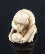 A Japanese ivory netsuke of a monkey viewing an insect through a magnifying glass, signed