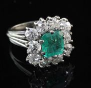 A mid to late 20th century white gold, emerald and diamond cluster dress ring, with reeded shank and