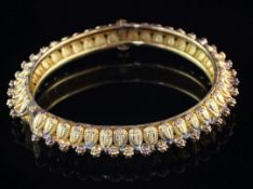 A Middle Eastern Etruscan style 22ct gold hinged bangle, with raised stylised leaves and flower head