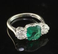 A mid 20th century 18ct white gold, emerald and diamond three stone ring, the central emerald