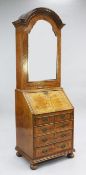 A Queen Anne style dome top walnut bureau bookcase, with single mirrored door above fall front and