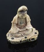 A Chinese soapstone seated figure of Guanyin, 18th century, seated on a rockwork base, with remnants