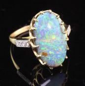 An 18ct gold and white opal ring with round brilliant cut diamond set shoulders, the oval opal