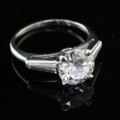 A platinum and single stone diamond ring with trapeze cut diamond set shoulders, the central round