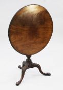 A fine George III mahogany tea table, with ribbon and flowerhead carved circular tilt top, on turned