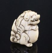 A Japanese ivory netsuke of a shi-shi, Edo period, seated and holding a ball, 4cm