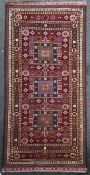 A Caucasian rug, with three central geometric medallions in a field of geometric motifs, on a red