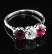 An early 20th century platinum and three stone ruby and diamond ring, the cushion cut diamond