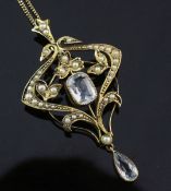 An Edwardian 9ct gold, aquamarine and split pearl drop pendant brooch, of scrolling design, on a