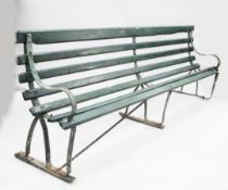 A large green painted railway station bench, with wrought iron sides and wooden slats