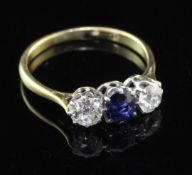 An 18ct gold and three stone sapphire and diamond ring, the central oval cut sapphire flanked by two
