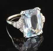 A white gold, aquamarine and diamond set dress ring, the central fancy emerald cut aquamarine