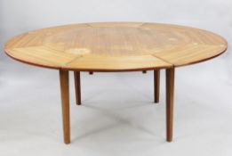 A Danish Dyrlund teak circular extending dining table, with unusual quarter segmented slide out