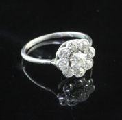 A white gold and diamond cluster ring, of flower head design and set with nine round cut stones,