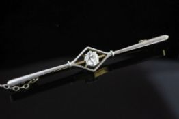 A 20th century gold, platinum and solitaire diamond bar brooch, the central diamond shaped motif set