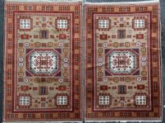 A pair of Kazak rugs, with central hooked medallion in a field of geometric motifs, on a beige