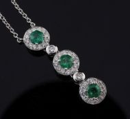 An 18ct white gold, emerald and diamond triple cluster drop pendant necklace, pendant 1in.