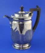 An Edwardian silver hot water jug, of cylindrical form, with gadrooned border and circular foot,