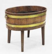 An oval brass bound mahogany open wine cooler on stand, with twin brass handles, on tapering