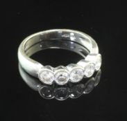 An 18ct white gold and five stone diamond half hoop ring, the collet set stones with an estimated