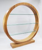 A large modern circular walnut open bookcase, with three plate glass shelves and a rectangular block