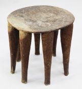 A Nupe stool, the circular top with incised geometric decoration above eight legs, H.1ft 6.5in.