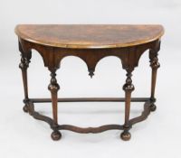 A 17th century style walnut demi lune table, with arched frieze, on turned supports united by shaped