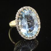 A gold, aquamarine and diamond set dress ring, the large fancy oval cut aquamarine bordered by