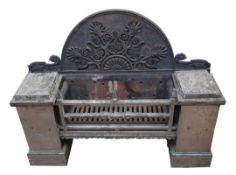 A large Regency polished steel and cast iron fire grate, the arched back with applied Anthemion