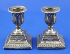 A pair of George III silver dwarf candlesticks, with engraved armorial and beaded and foliate