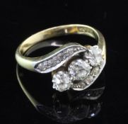 An 18ct gold three stone diamond ring in a diamond twist setting, the three largest stones with a