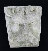 A shaped limestone keystone, relief carved with a gargoyle mask, 11in.