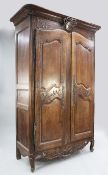 A large 19th century French walnut armoire, with central quiver of arrows and ribbon tied crest