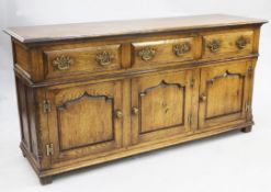A George III style oak dresser base, with three frieze drawers above three cupboard doors, with