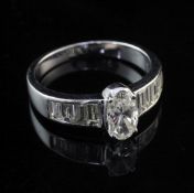 A 14ct white gold and diamond dress ring, set with central oval cut diamond and graduated baguette